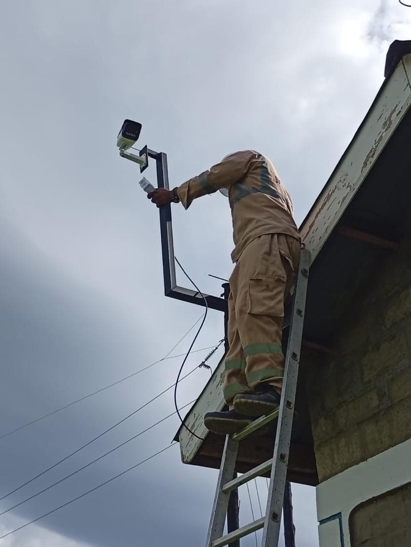 A Xinix technician fitting a camera to its bracket at a roof edge